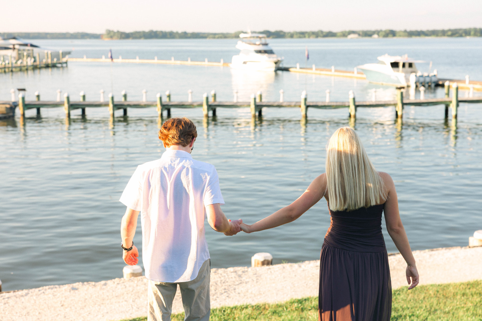 Samantha and Colin holding hands, walking down toward the water at the marina
