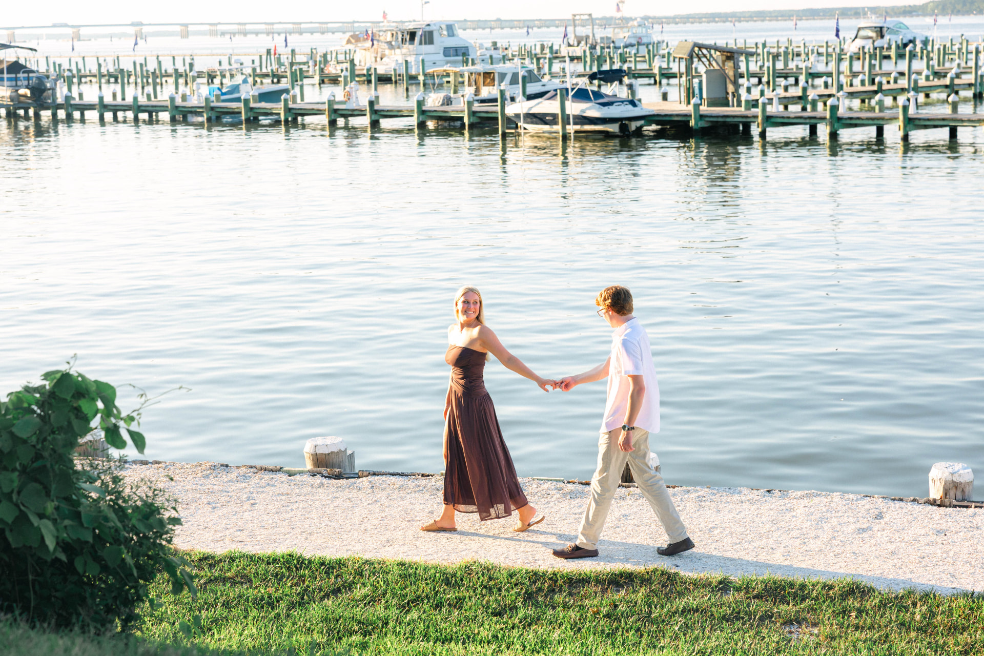 Samantha leading Colin by the hand along the water past the marina